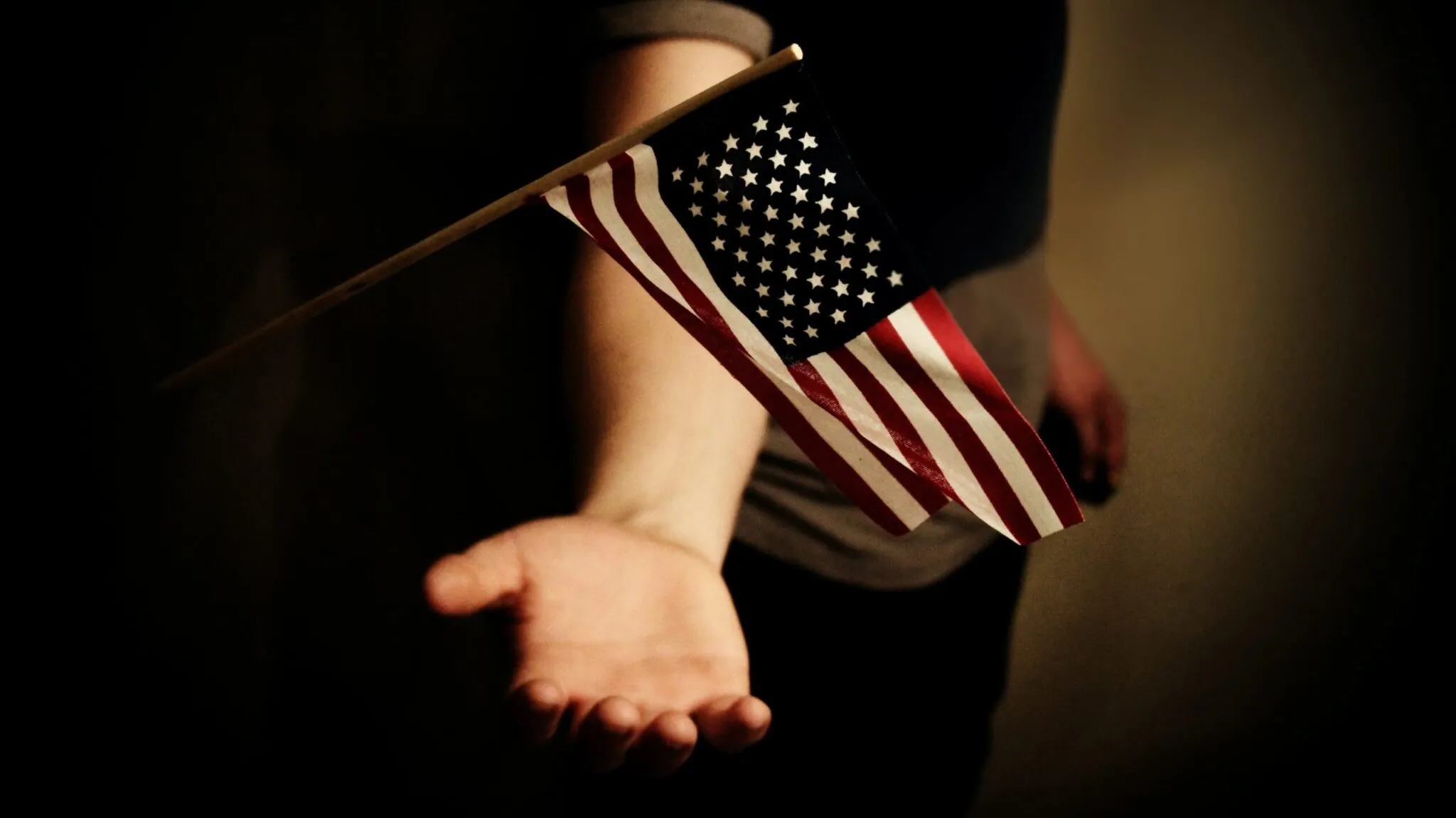 A hand palm open holding the American flag. Celebrating passing their US Naturalization Test after studying our guide to success.